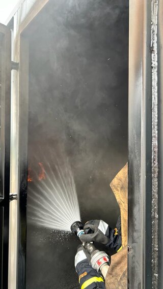 Eine Person löscht einen Brand in einer Realbrandausbildung im Feuerwehrtechnischen Zentrum in Pfaffenhain. Foto: eins