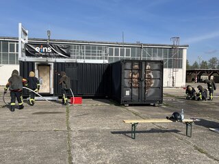 Kameradinnen und Kameraden üben an einem Feststoffbrandcontainer. Foto: eins