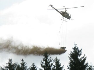 Ein Hubschrauber bringt über einem Waldstück Kalk zum Schutz des Waldbodens aus. Foto: Frank Knebel/ Archiv